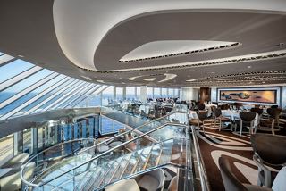 A panoramic view of the elegant MSC Yacht Club Restaurant featuring glass walls and stylish seating arrangements | MSC Cruises