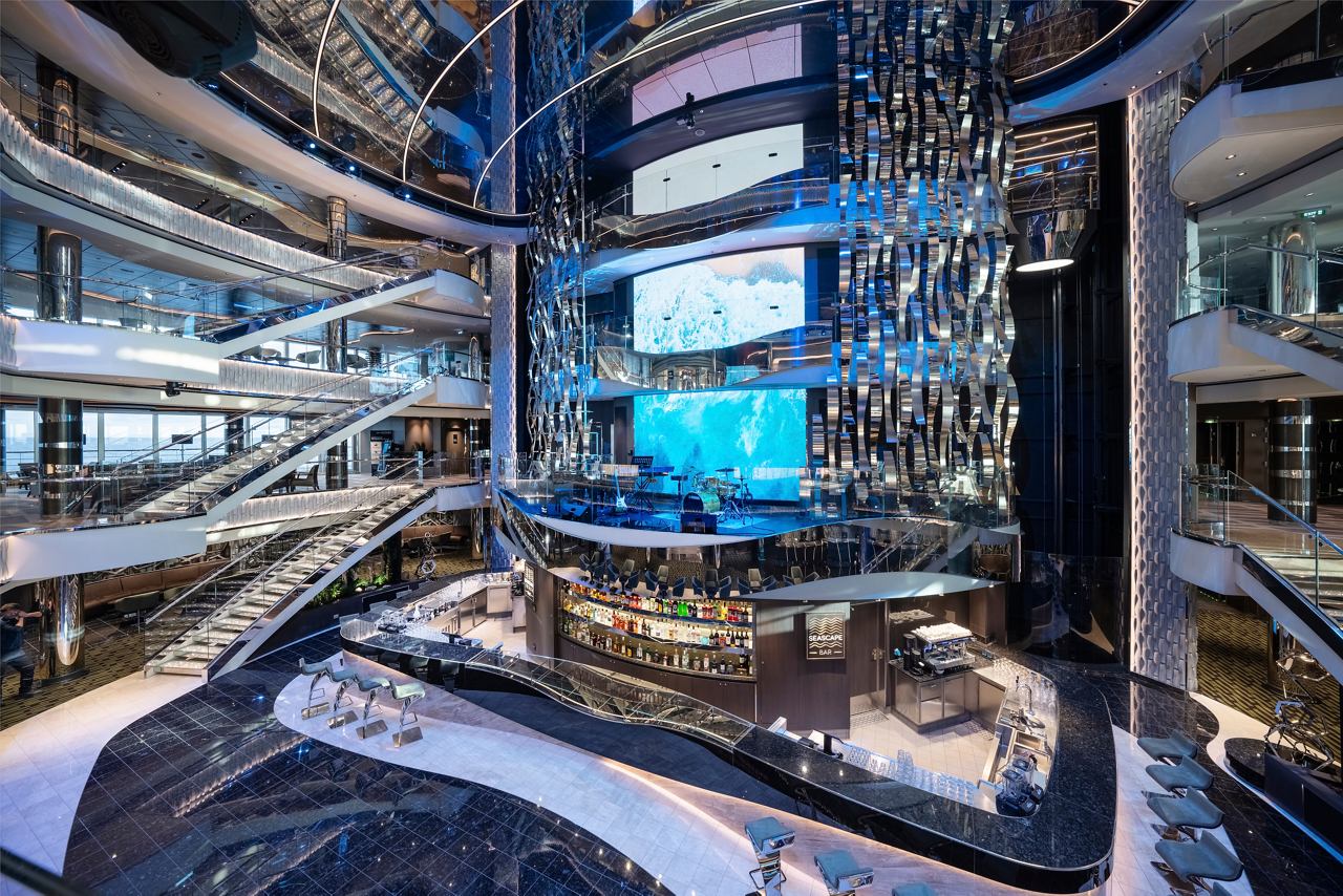 A vibrant lounge area featuring the Seascape Bar with a sleek counter, elegant decor, and a piano for live music | MSC Cruises
