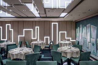 Elegant dining setup in a modern restaurant with a skyline mural, inviting guests to enjoy a memorable meal | MSC Cruises