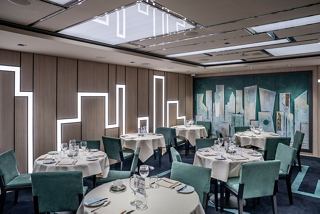 Elegant dining space featuring round tables, green chairs, and artistic wall decor, inviting guests to enjoy a meal together | MSC Cruises