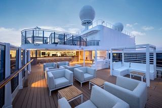 Outdoor bar with counter and seating on MSC Seascape at dusk | MSC Cruises