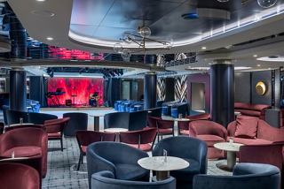 A stylish lounge with comfortable seating and a vibrant stage for live performances | MSC Cruises