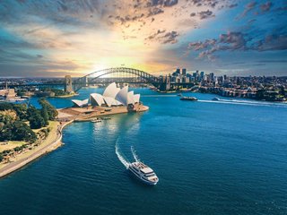 Vue aérienne du port de Sydney avec un bateau et des monuments emblématiques au coucher du soleil | MSC Cruises