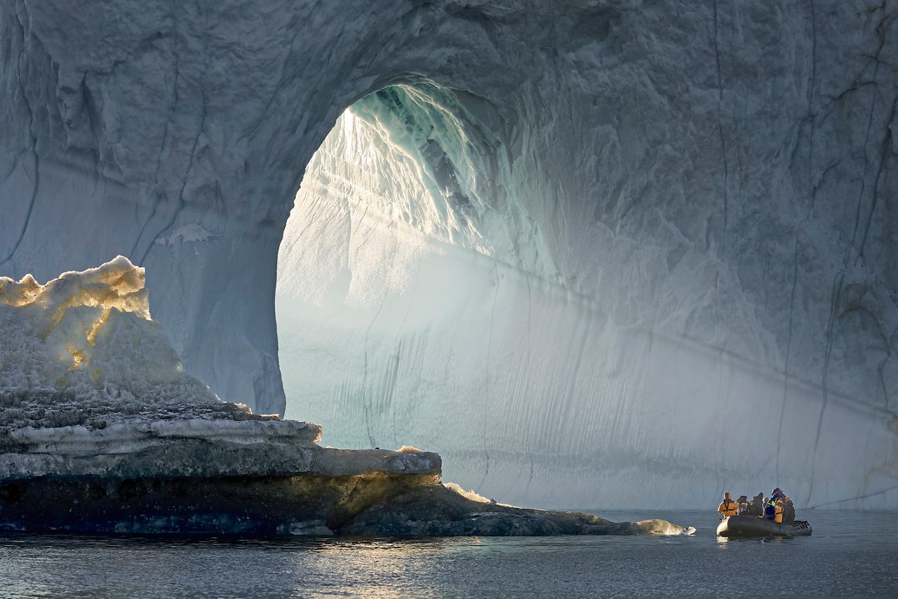 A serene view of a boat navigating through icy waters near a majestic glacier in Greenland | MSC Cruises
