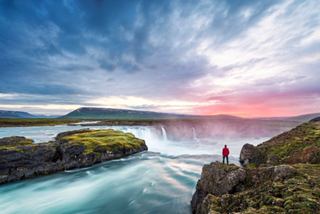 A serene view of a man enjoying the natural beauty near Godafoss Waterfall in Iceland's stunning landscape | MSC Cruises