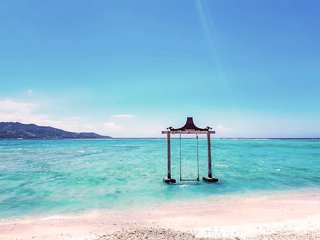 A wooden swing stands above turquoise sea at the beach in Lombok, Indonesia | MSC Cruises