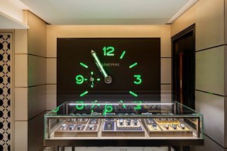 A stylish watch showcase featuring luxury timepieces illuminated by green lighting in the MSC Seascape shop | MSC Cruises