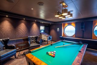 A vibrant pool room with a green table and porthole view, perfect for relaxation and socialising | MSC Cruises