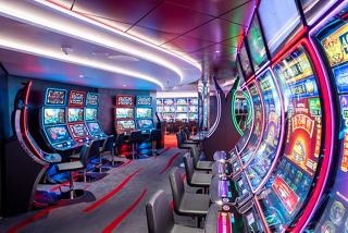 A modern casino area featuring vibrant slot machines and a bar counter on MSC Seascape | MSC Cruises