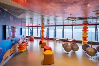 A vibrant space designed for family entertainment featuring colourful seating, large windows, and interactive games | MSC Cruises