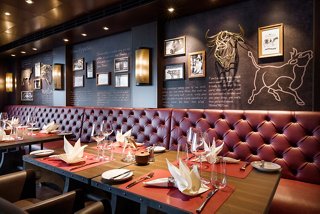 Un área de comedor cálida y acogedora con asientos cómodos y decoración elegante en el restaurante Butcher's Cut | MSC Cruceros
