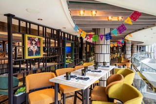 A vibrant dining area featuring tables and colourful decor at Hola! Tacos & Cantina on MSC Seascape | MSC Cruises