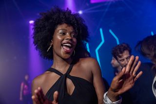 A joyful woman dances at a vibrant disco party, surrounded by friends, celebrating life on board MSC World Europa | MSC Cruises