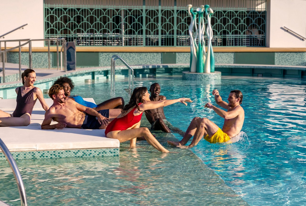 A joyful group of friends enjoying time together by the pool on MSC World Europa | MSC Cruises