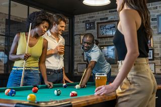 Des amis profitent d'une partie de billard tout en partageant des boissons et des rires dans une zone de divertissement animée à bord | MSC Cruises