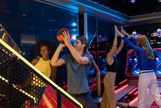 A group of friends enjoy a lively game at the arcade, creating joyful memories together | MSC Cruises