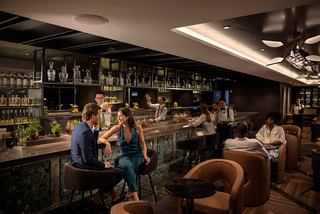 Un couple déguste des cocktails au Elixir Mixology Bar sur MSC World Europa, avec un personnel attentif créant une ambiance chaleureuse | MSC Croisières