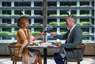 Una pareja brinda con vino en una mesa de restaurante rodeada de una vibrante exhibición de vinos | MSC Cruceros