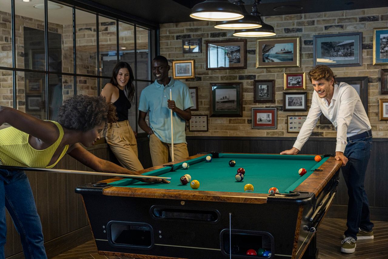 Des amis profitent d'une partie de billard dans un bar animé à bord du MSC World Europa | MSC Croisières