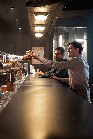 A bartender serves beer to a guest at the bar counter on MSC World Europa, showcasing the lively atmosphere on board | MSC Cruises
