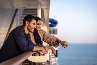A couple enjoys the sea view from the deck, pointing towards the horizon in a moment of connection and adventure | MSC Cruises