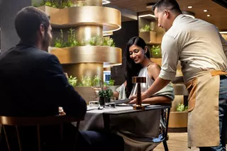 A man and woman seated at a restaurant table on a cruise | MSC Cruises
