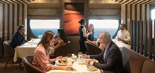 An older couple enjoying dinner in a restaurant with a sea view | MSC Cruises