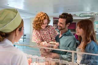 A family enjoys sweet treats together at a bar while a friendly crew member assists them | MSC Cruises