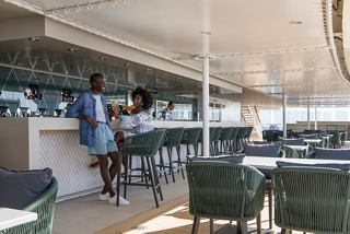 A couple enjoys drinks at the bar counter in the exclusive solarium aboard MSC World Europa | MSC Cruises