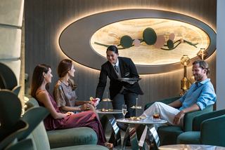 Gäste genießen einen wunderbaren Moment mit einem Butler, der Getränke in der eleganten Top Sail Lounge serviert | MSC Cruises
