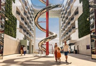 Familias disfrutando de la vibrante atmósfera en el Paseo Mundial, con el emocionante tobogán Venom Drop a la vista | MSC Cruceros