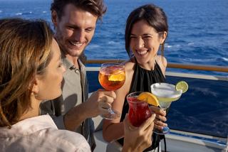 Friends enjoying colourful cocktails together on a cruise ship deck with a beautiful sea view in the background | MSC Cruises