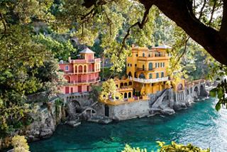 Una vista panoramica di edifici colorati sul mare a Portofino, circondati da verdeggiante vegetazione e scogliere rocciose | MSC Crociere