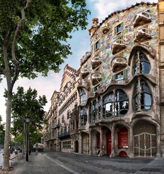 Ein schöner Blick auf Casa Batllò in Barcelona, der ihre einzigartige Architektur entlang einer von Bäumen gesäumten Straße zeigt | MSC Cruises