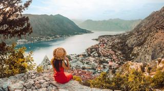 A woman in a red dress enjoys a panoramic view of Kotor's stunning landscape and sea | MSC Cruises
