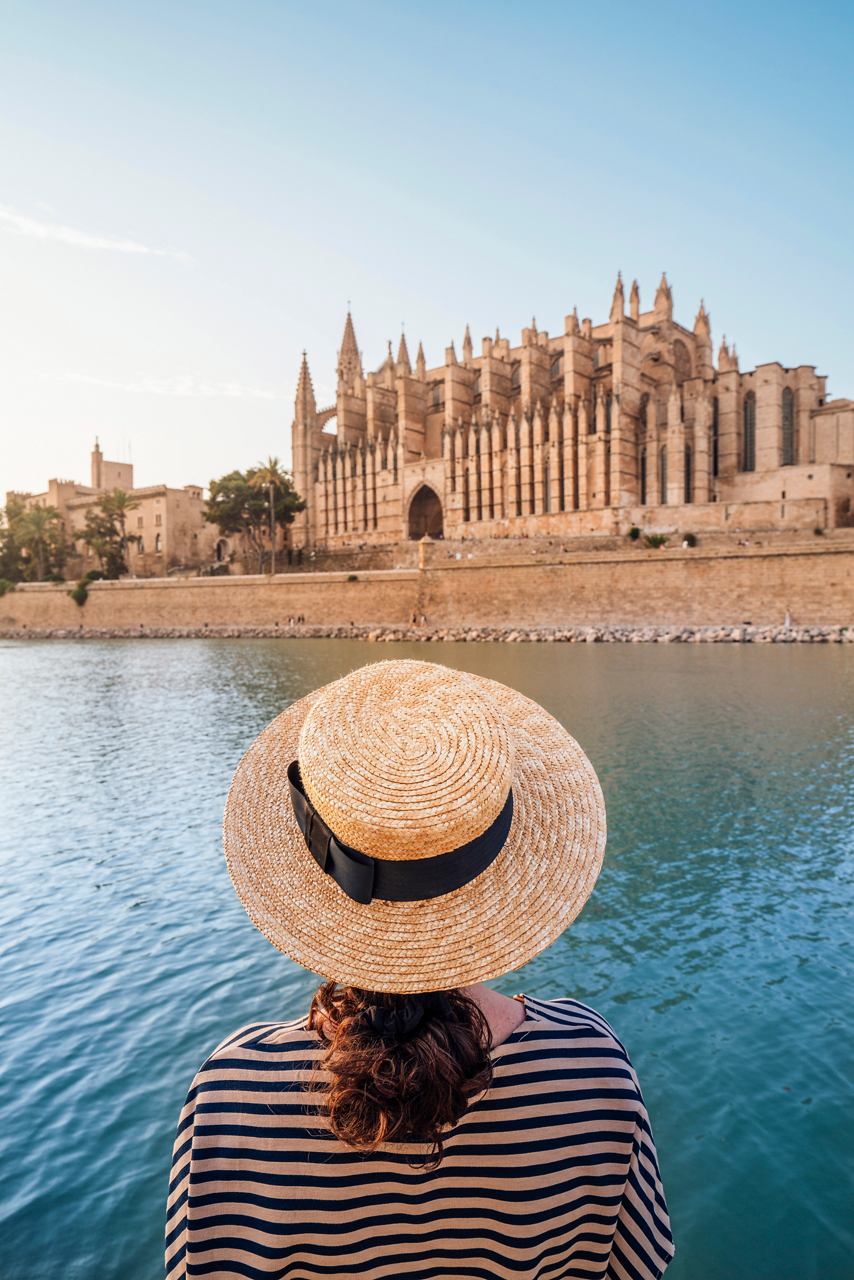 A woman in a hat gazes at the Cathedral of la Seu by the sea in Palma de Mallorca, Spain, inviting exploration | MSC Cruises