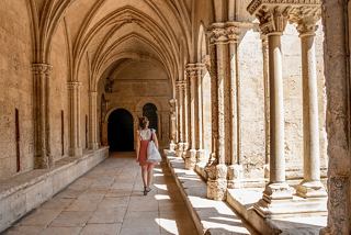 A woman walks through a beautiful cloister in Arles, France, surrounded by stunning architecture and warm light | MSC Cruises