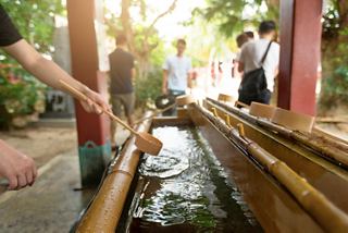 Visitors participate in a ceremonial water ritual at Naminoue Shrine in Naha, Japan, surrounded by lush greenery | MSC Cruises