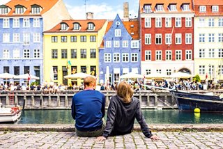 Un couple profite d'une journée d'été le long du canal, entouré de bâtiments colorés à Nyhavn, Copenhague | MSC Croisières