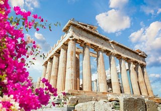 The Parthenon stands majestically against a blue sky, surrounded by vibrant flowers and rich Mediterranean history | MSC Cruises