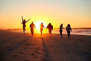A group of young peopole joyfully jumping on the beach during a vibrant sunset | MSC Cruises