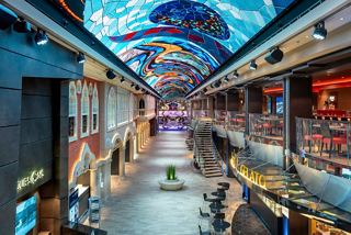 A vibrant promenade featuring dining options and lively entertainment under a colourful LED dome | MSC Cruises