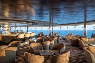 A stylish bar with comfortable seating and a stunning sea view through glass walls | MSC Cruises
