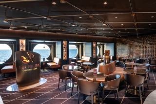 A spacious lounge area with comfortable seating and large windows offering views of the sea | MSC Cruises