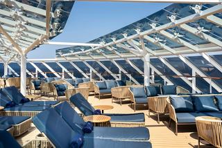 Eine ruhige Sonnenterrasse mit Liegen und einer Bar, die zur Entspannung im MSC Yacht Club einlädt | MSC Cruises