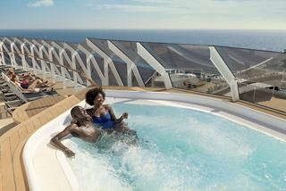 A couple relaxes together in a whirlpool bath on the ship’s deck, enjoying stunning sea views | MSC Cruises