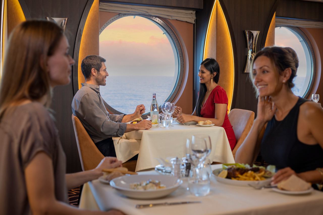 Des couples savourent un délicieux dîner au restaurant La Foglia avec vue sur le coucher de soleil à travers le hublot | MSC Cruises
