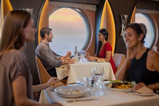 Des couples savourent un délicieux dîner au restaurant La Foglia avec vue sur le coucher de soleil à travers le hublot | MSC Croisières