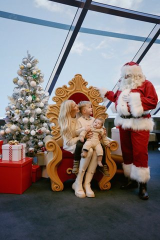 Una familia disfruta de un momento festivo con Santa Claus cerca de un árbol de Navidad decorado y regalos a bordo del MSC Virtuosa | MSC Cruceros