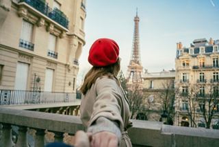 A woman wearing a red hat gazes at the Eiffel Tower in Paris, surrounded by beautiful architecture | MSC Cruises